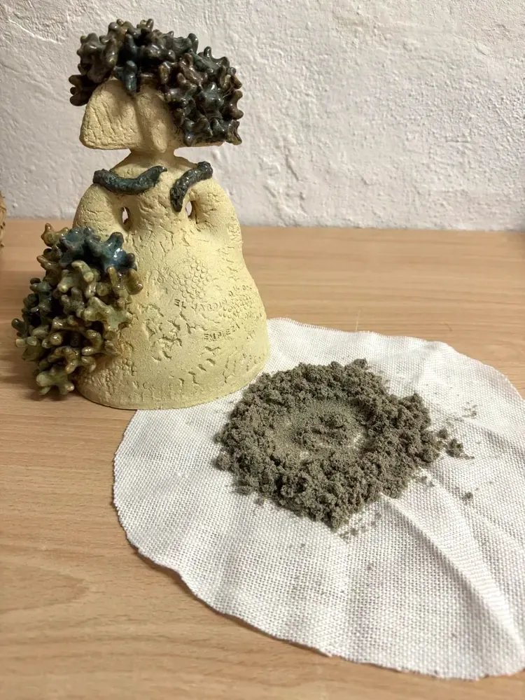 Un puñado de arena del fondo, sobre una tela de lino, junto a la pieza