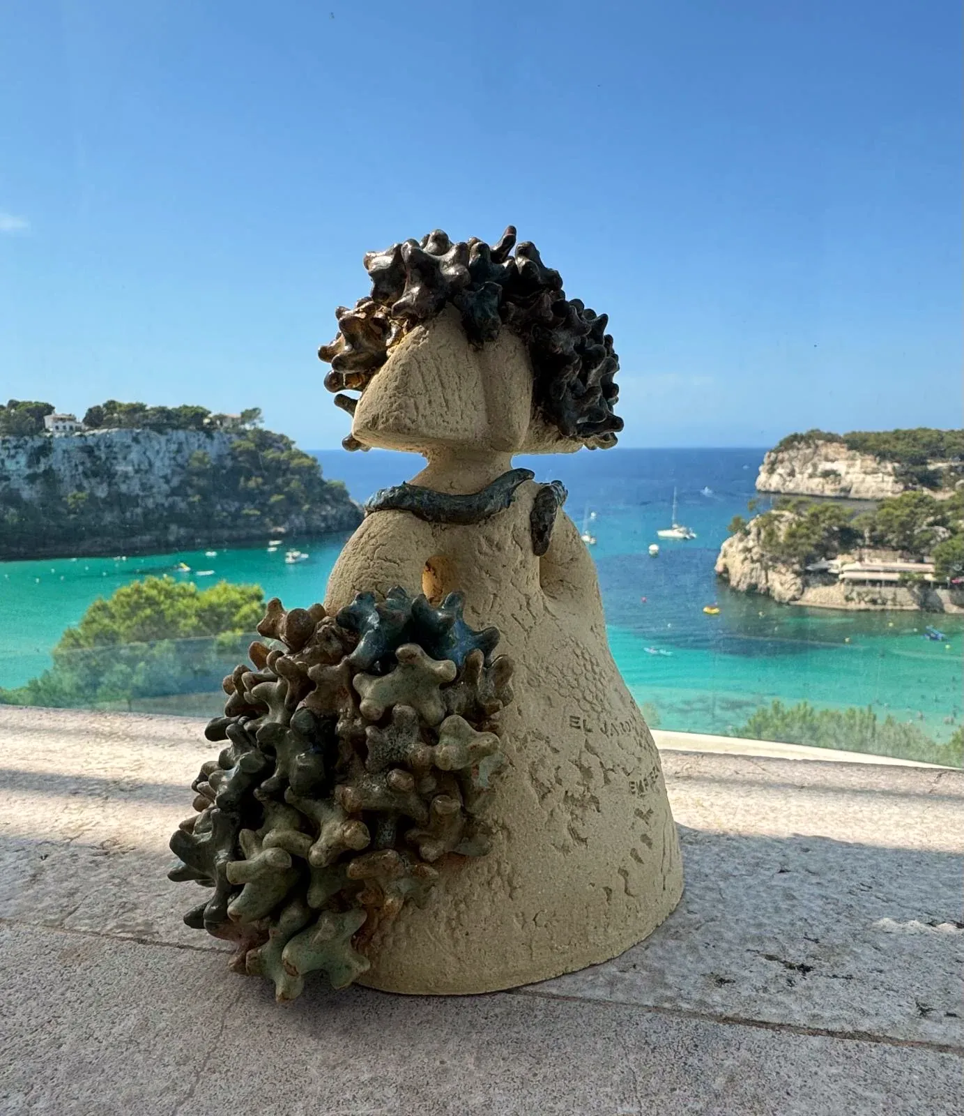 Menina del Mar con corales verdes, frente a una cala de aguas turquesa
