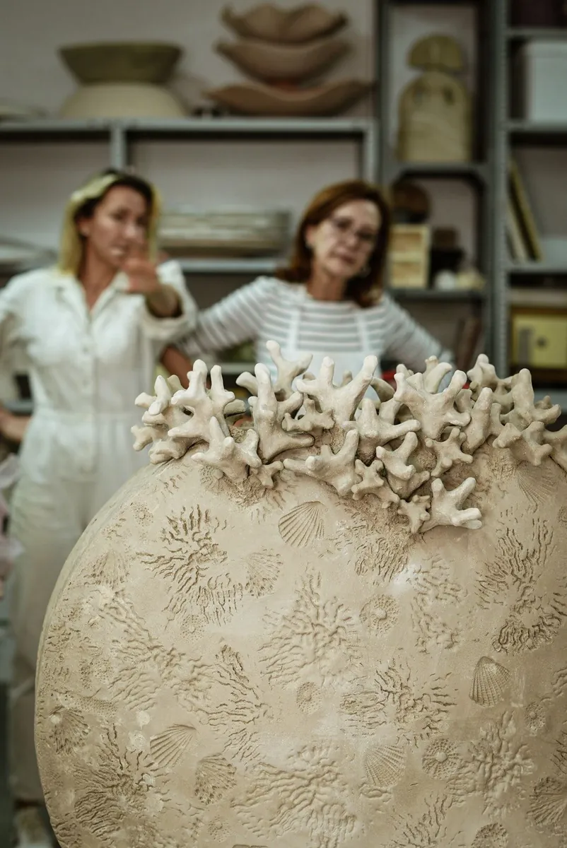 Las improntas de conchas y erizos en el cuerpo del jarrón, con las dos autoras al fondo