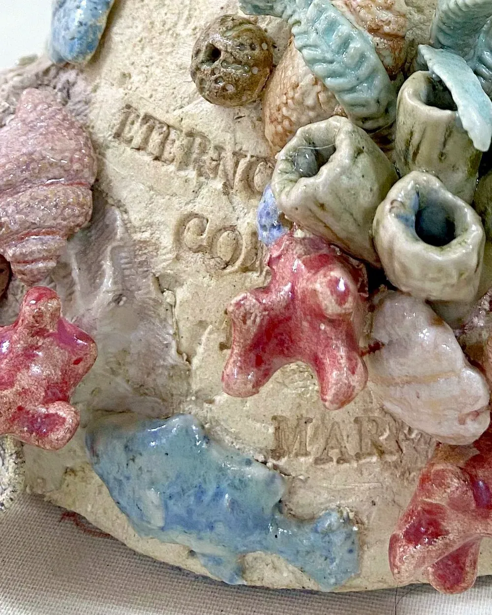 La frase «Eterno como el mar», grabada a mano sobre el gres entre los corales esmaltados